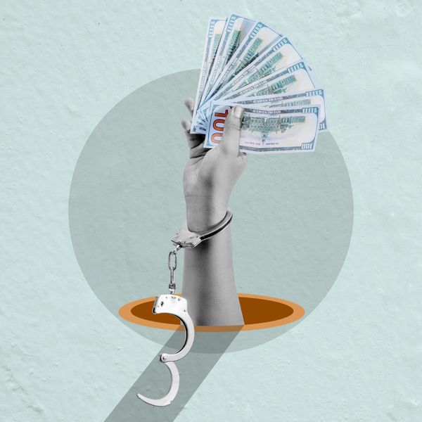 A freed hand holding cash as the handcuff falls open